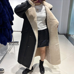 Person wearing a long black coat with beige lining in a store setting.