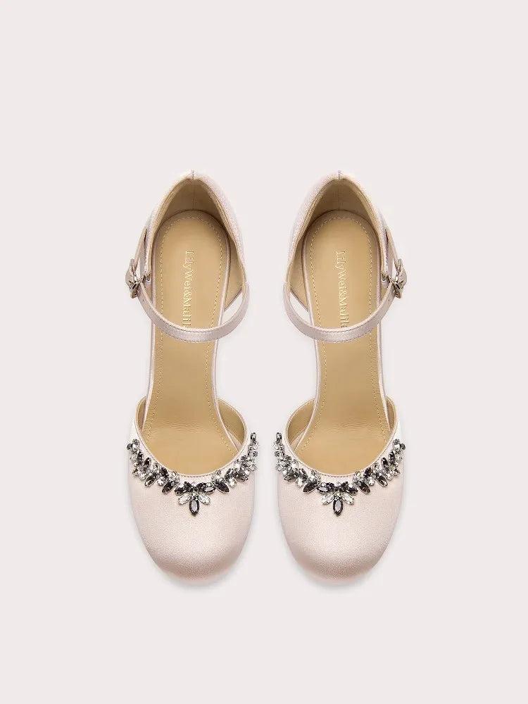 Pair of beige shoes with decorative embellishments on a white background