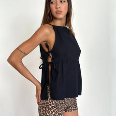 Woman wearing a black sleeveless top with lace-up back and leopard print shorts on a white background