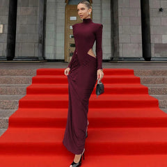 Woman in a burgundy dress walking up red steps in front of a building.