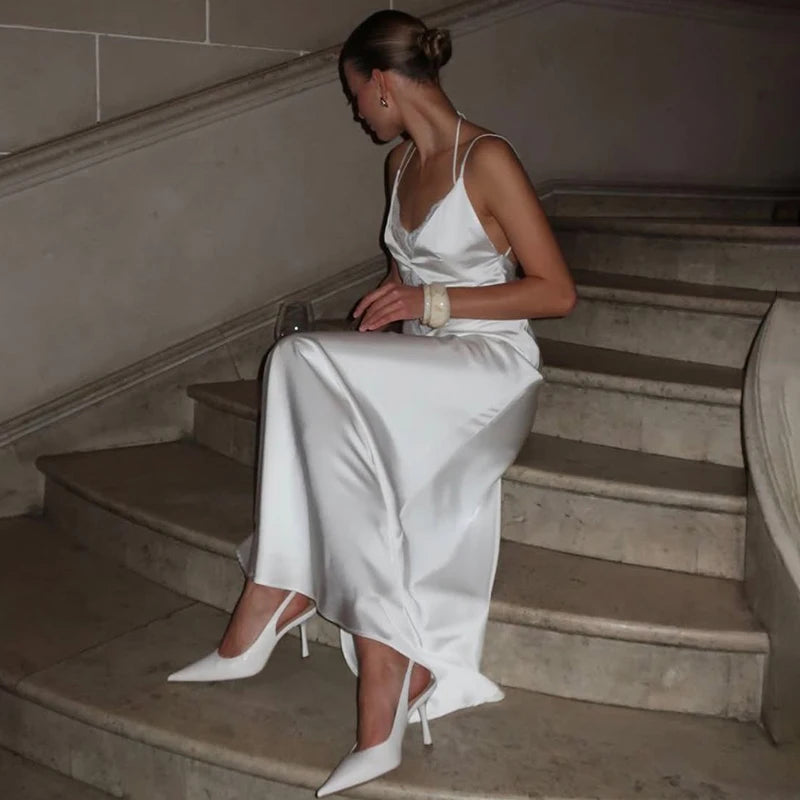 Woman in a white satin dress sitting on a staircase.
