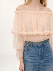 Light pink off-shoulder blouse with ruffled detail and flowing sleeves.