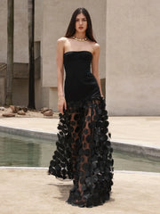 Woman wearing a black strapless gown with floral details in an outdoor setting.