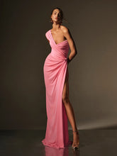 Woman wearing a pink evening gown with a high slit on a dark background