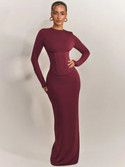 Woman wearing a burgundy evening gown against a plain background