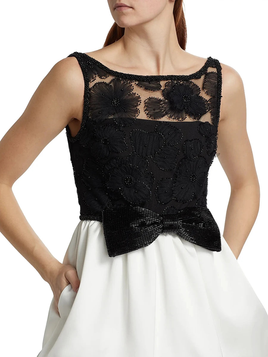 Black lace top with a bow detail worn by a person on a white background