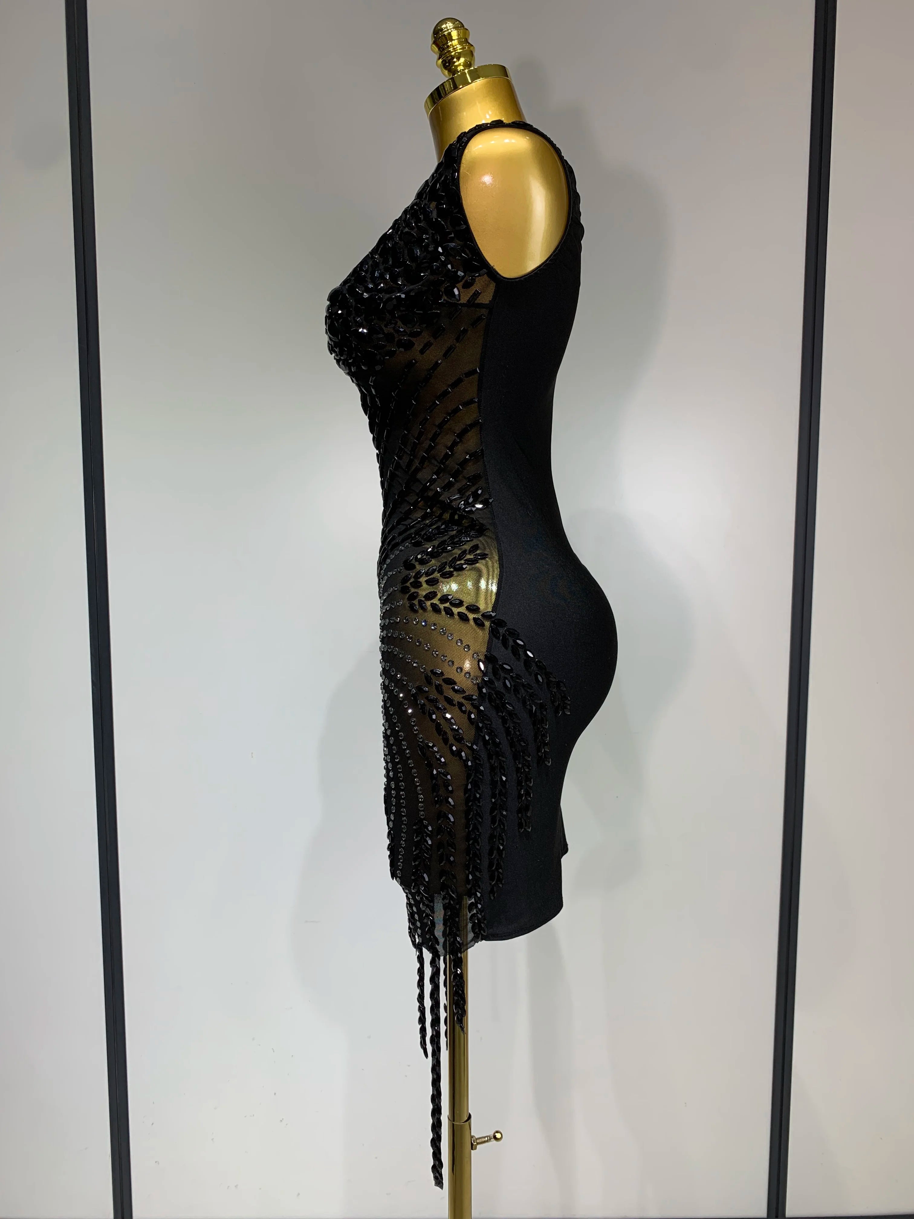 Black beaded dress on a mannequin against a plain background