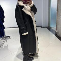 Person wearing a black coat with white fur lining in a room.