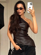 Woman taking a mirror selfie wearing a brown one-shoulder top and black pants.