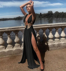 Woman in a black dress with gold detailing by a lakeside.