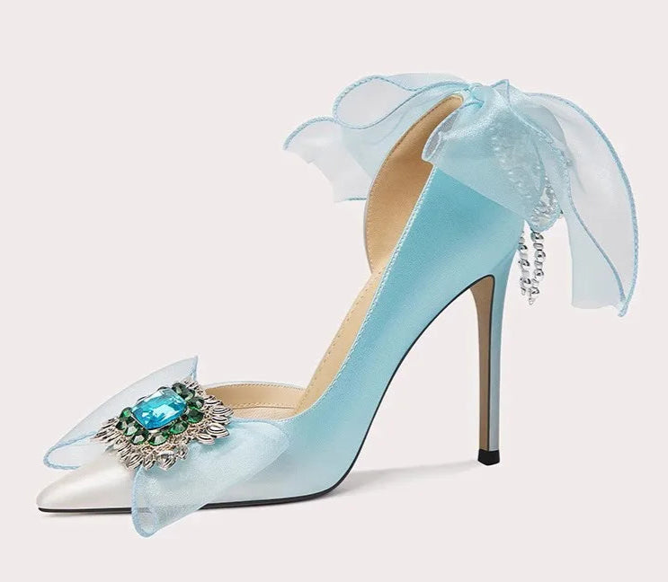 Light blue high-heeled shoe with decorative bow and gemstone on a white background