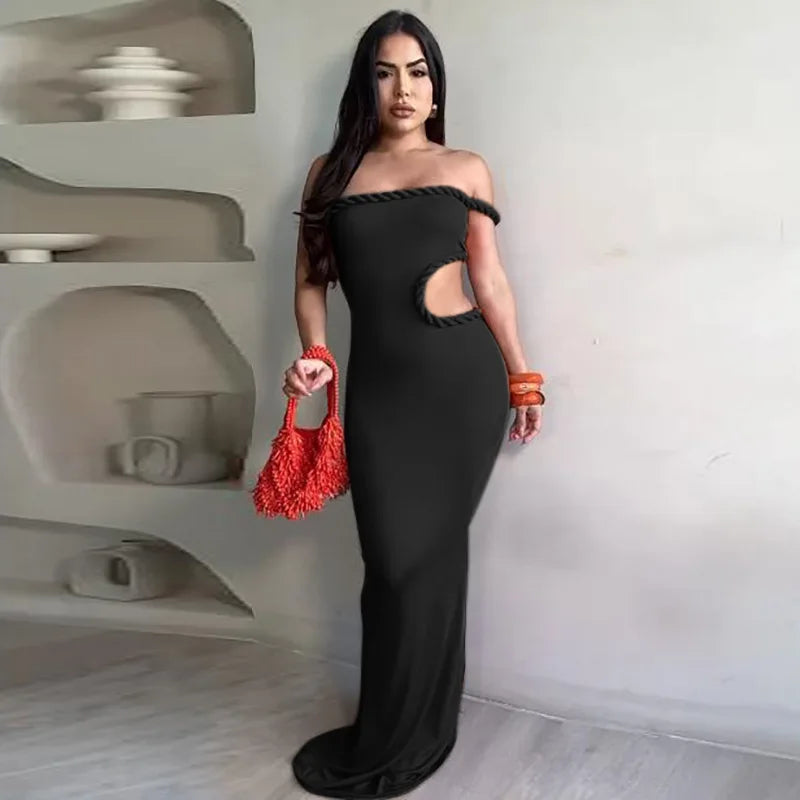 Woman in a black off-shoulder dress holding a red handbag in a modern interior setting.