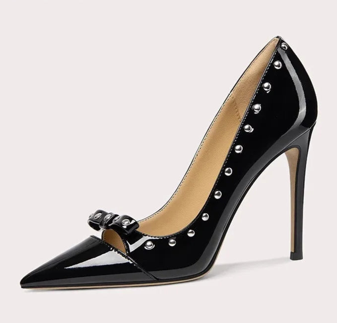 Black high-heeled shoe with studded details on a light gray background