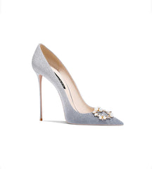 Silver glitter high heel shoe with a decorative brooch on a white background