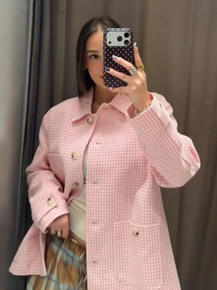 Person wearing a pink checkered coat taking a mirror selfie.