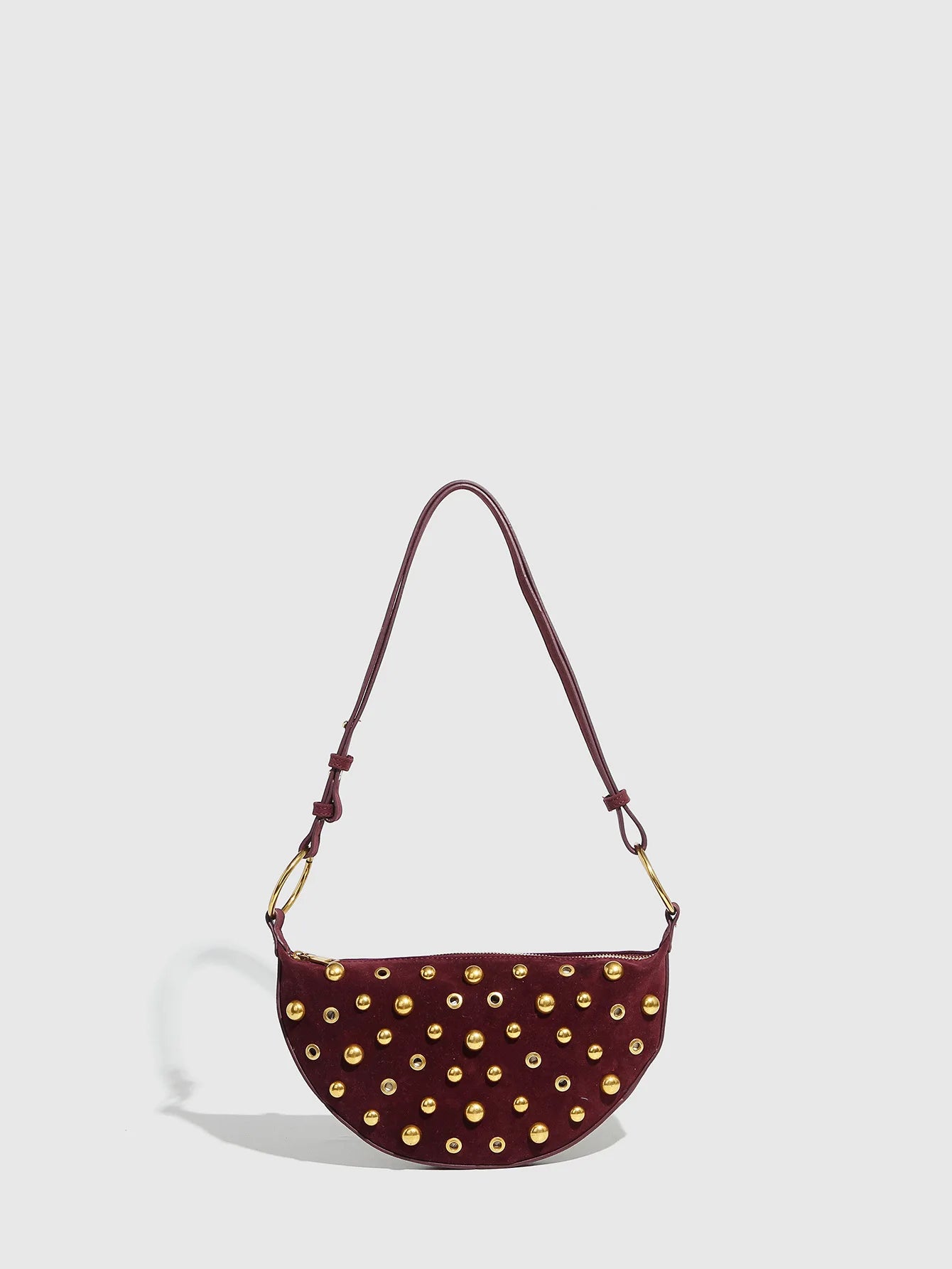 Maroon handbag with gold studs on a light gray background