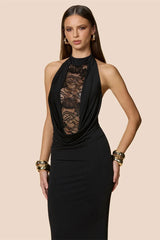 Woman wearing a black halter neck dress with lace detailing on a beige background