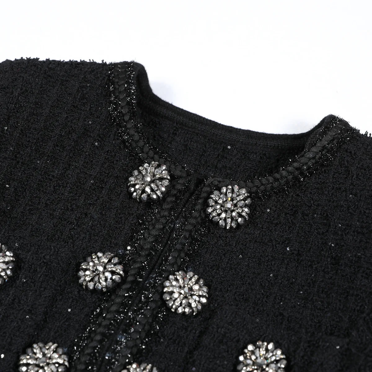 Black embroidered garment with silver embellishments on a white background