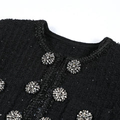 Black embroidered garment with silver embellishments on a white background