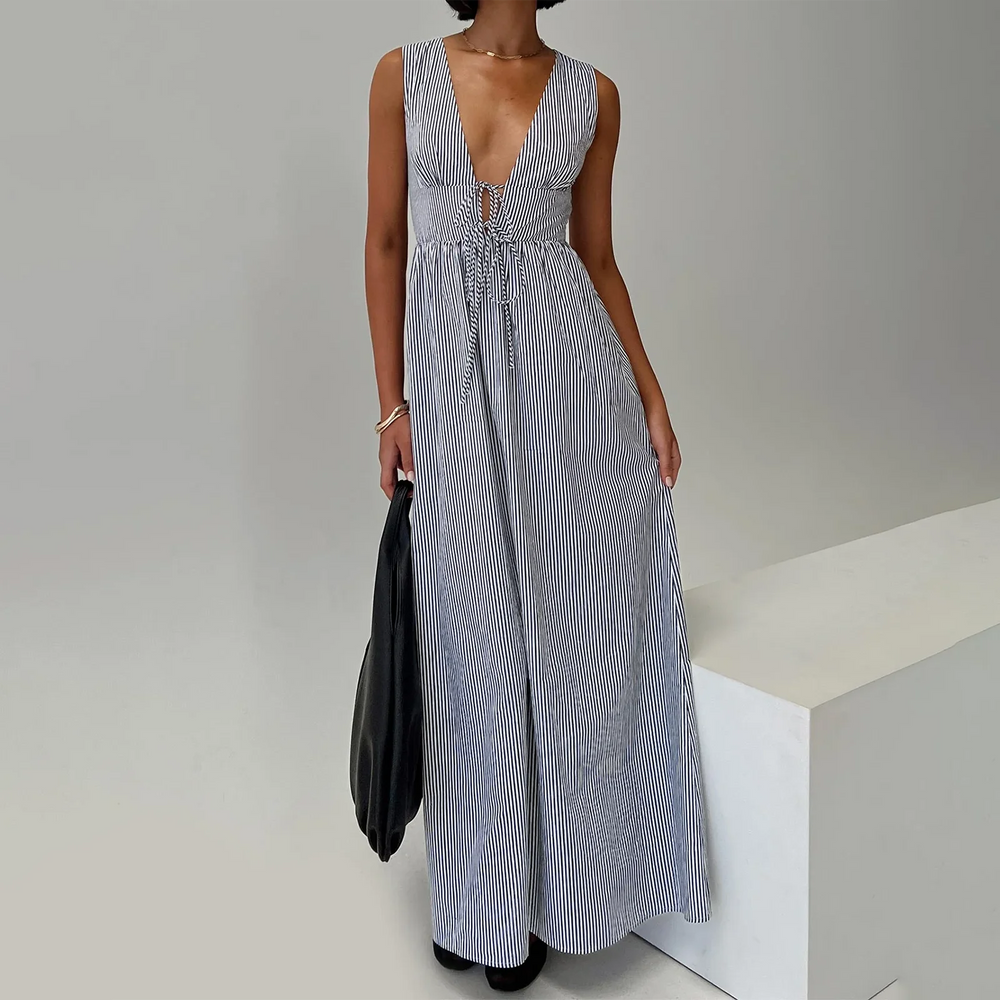 Woman wearing a long blue and white striped dress against a plain background