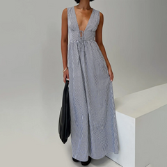 Woman wearing a long blue and white striped dress against a plain background