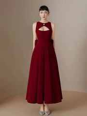 Woman wearing a burgundy dress with a cutout design on a beige background