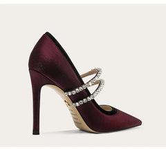 Maroon high-heeled shoe with crystal straps on a light beige background