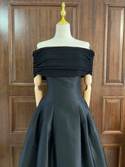 Black off-shoulder gown on a mannequin against a wooden panel background