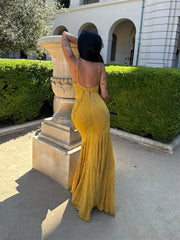 Woman in a yellow dress standing in front of a classical building with greenery.