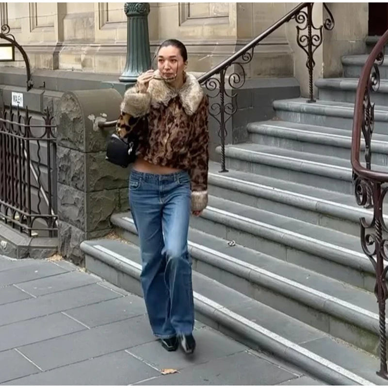 Person wearing a leopard print coat and blue jeans standing on stone steps.