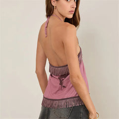 Woman wearing a pink top with fringe details on a plain background