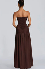 Woman wearing a strapless brown dress on a plain background