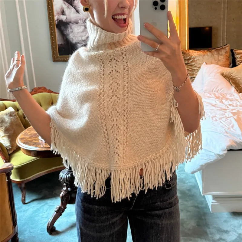 Beige knit poncho with fringe hem, worn by a model
