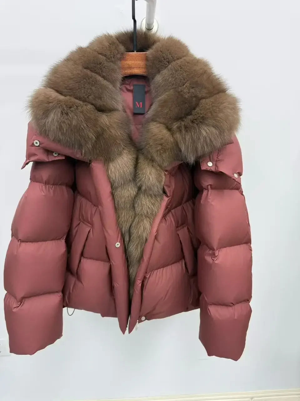 Pink puffer jacket with fur hood on a white background