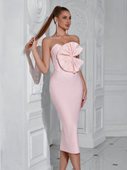 Woman wearing a pink strapless dress with a large bow detail in an elegant interior setting.
