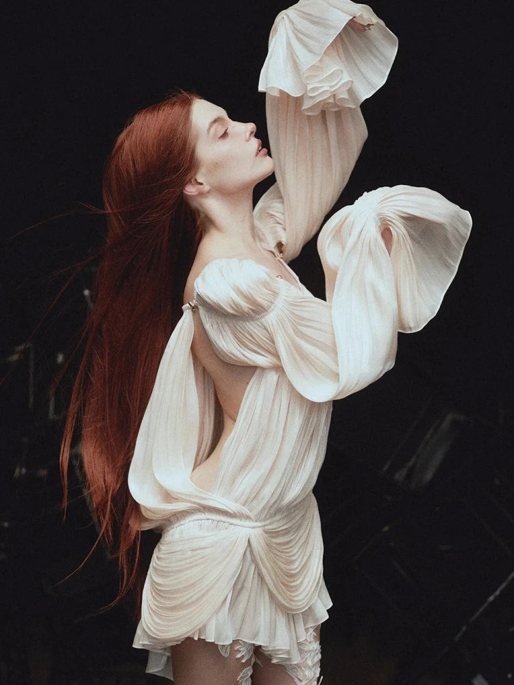 Woman in a flowing white dress against a dark background