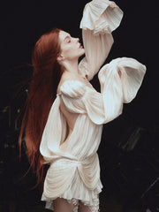 Woman in a flowing white dress against a dark background