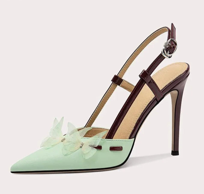 Mint green high-heeled shoe with a brown strap on a light gray background