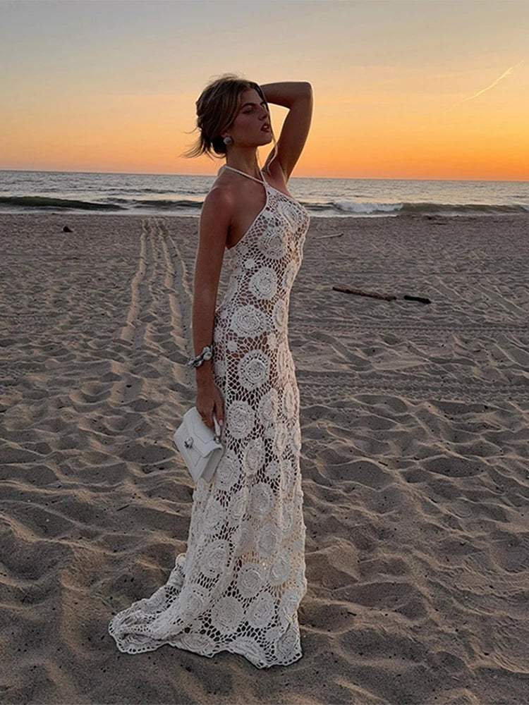 Woman in a white lace dress standing on a beach at sunset