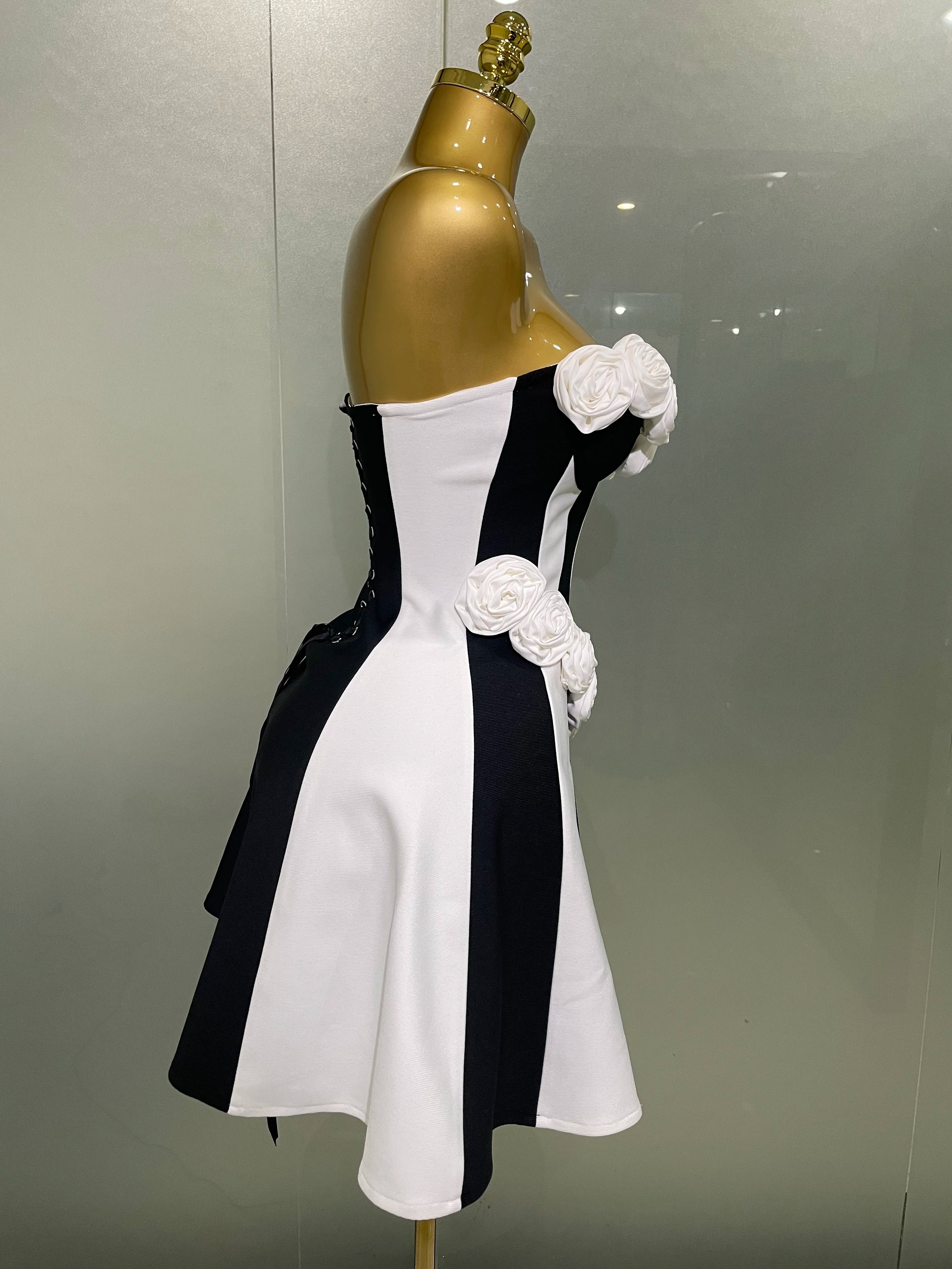 Black and white dress with floral details on a gold mannequin against a gray background