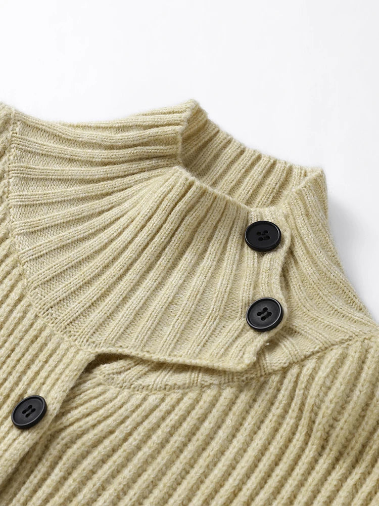 Close-up of a beige ribbed sweater with black buttons on a white background