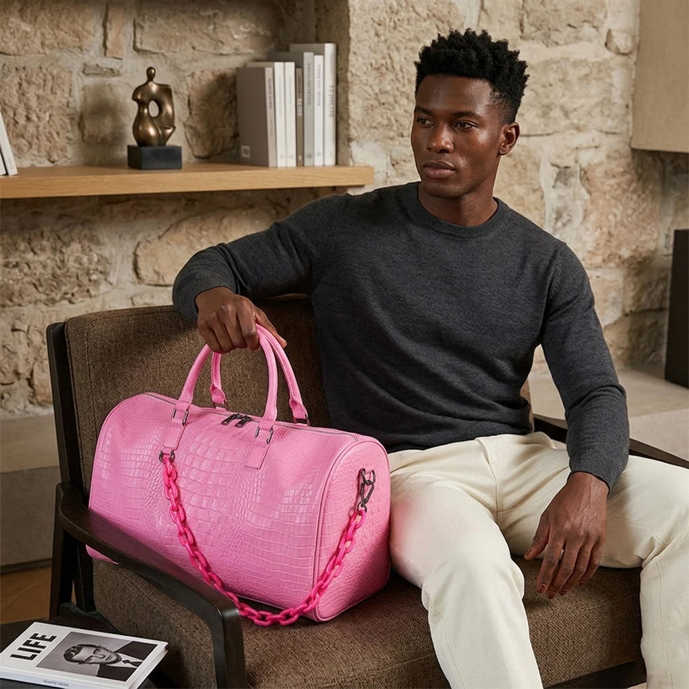 Man holding a pink crocodile embossed travel duffle bag