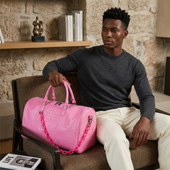Man holding a pink crocodile embossed travel duffle bag
