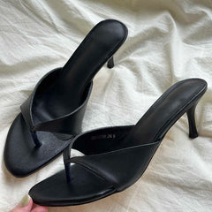 Black high-heeled sandals on a white fabric background