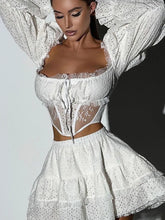 Woman wearing a white lace outfit against a plain background