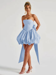 Woman wearing a light blue strapless dress with a ruffled skirt on a white background