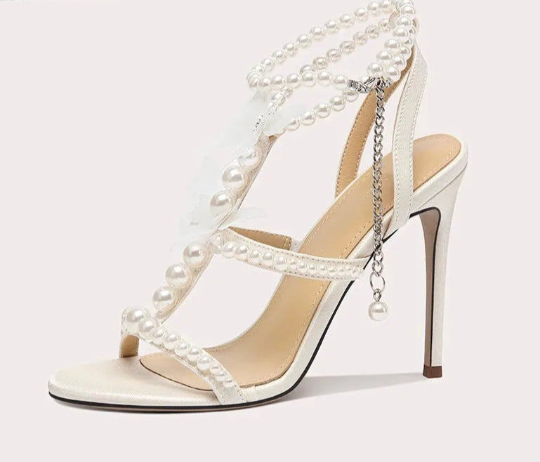 White high-heeled sandal with pearl embellishments on a white background