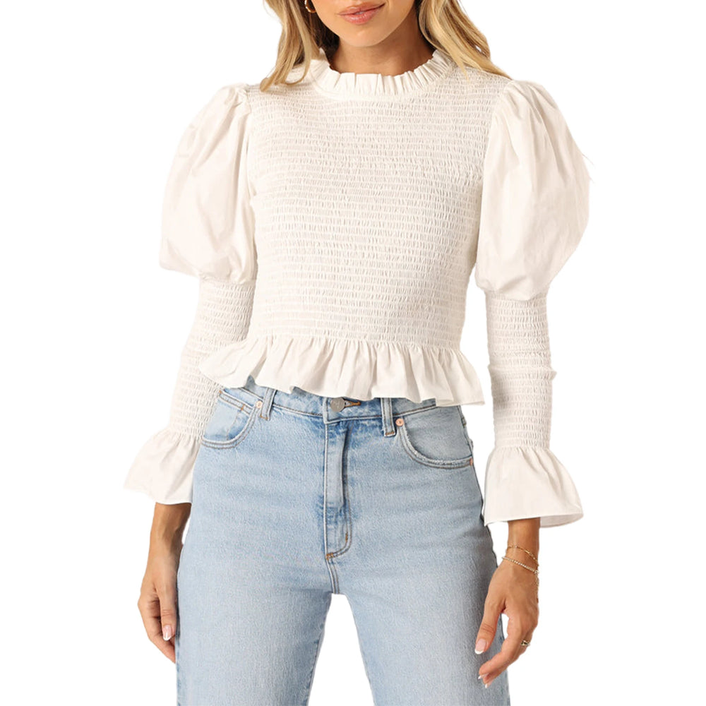 Woman wearing a white ruffled blouse and light blue jeans on a white background