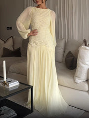Woman in a long, light-colored dress standing in a living room.