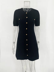 Black dress with gold buttons on a mannequin against a white background